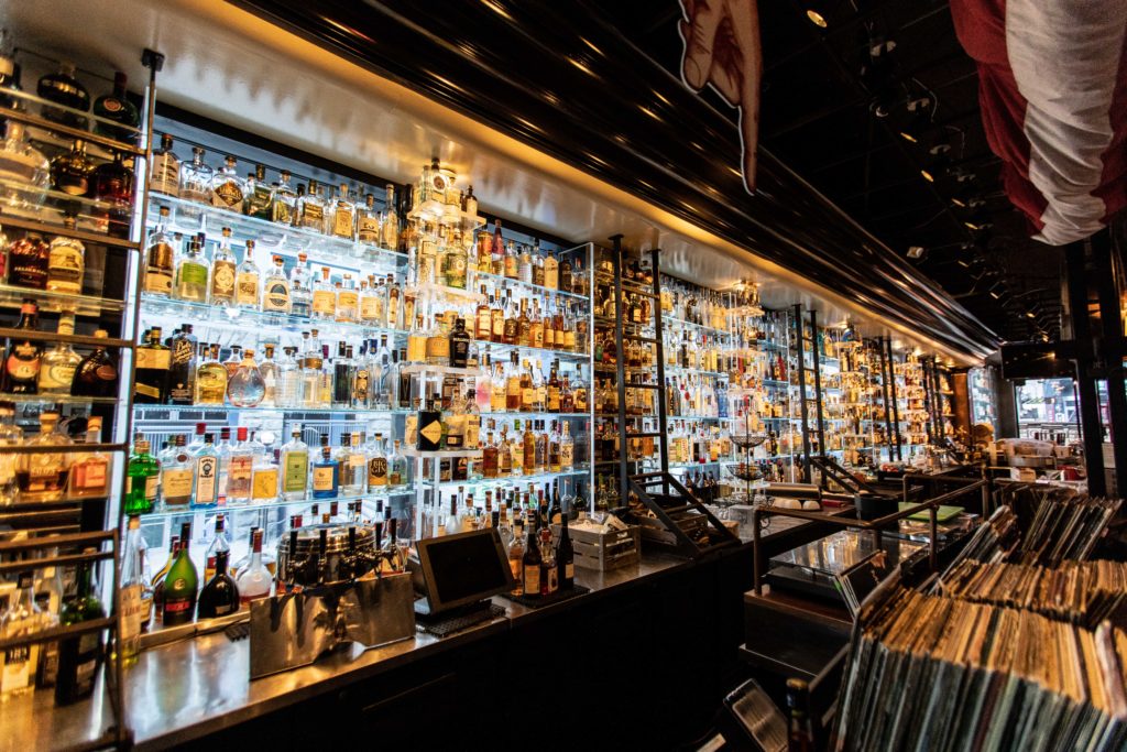 Image of a bar with over 1,000 neatly lined liquor bottles on the shelves. There is a window behind the bottles, illuminating them from behind.