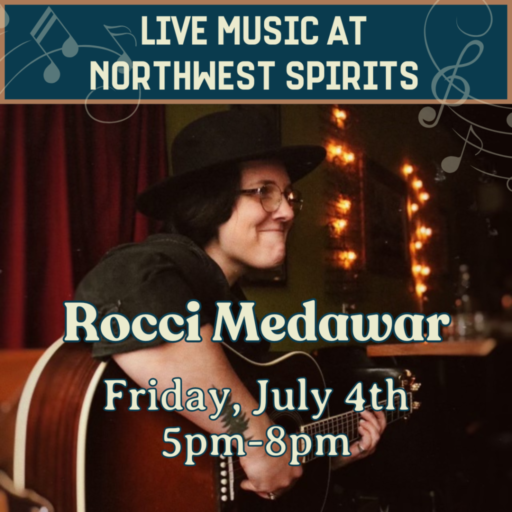 Promotional image for live music at Northwest Spirits featuring Rocci Medawar. Rocci, wearing a black hat and glasses, is smiling while playing an acoustic guitar in a cozy, warmly lit room. Text on the image reads: "Live Music at Northwest Spirits. Rocci Medawar. Friday, July 4th, 5pm–8pm."
