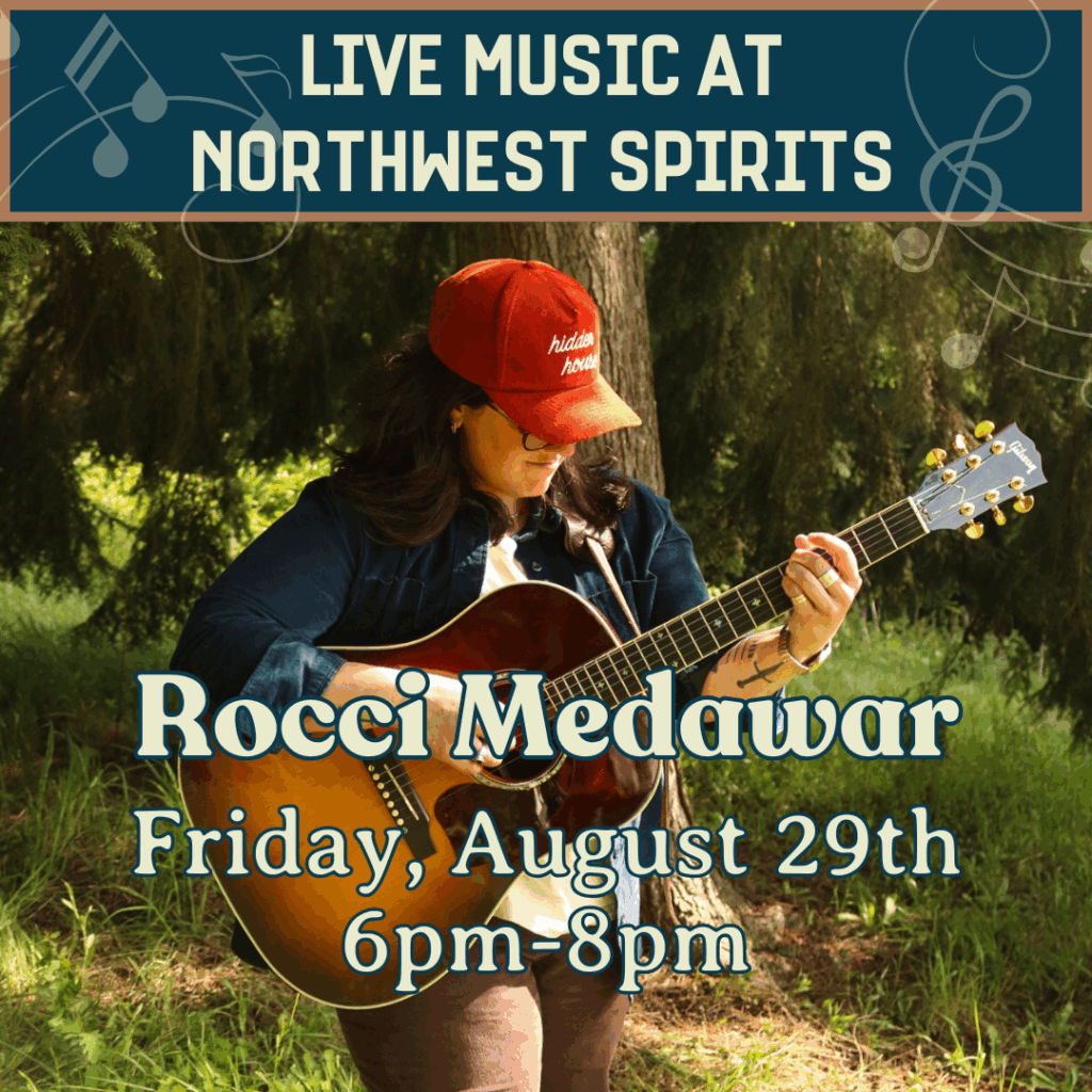 Rocci Medawar playing acoustic guitar in a wooded setting, promoting her live music performance at Northwest Spirits on Friday, August 29th from 6pm to 8pm.