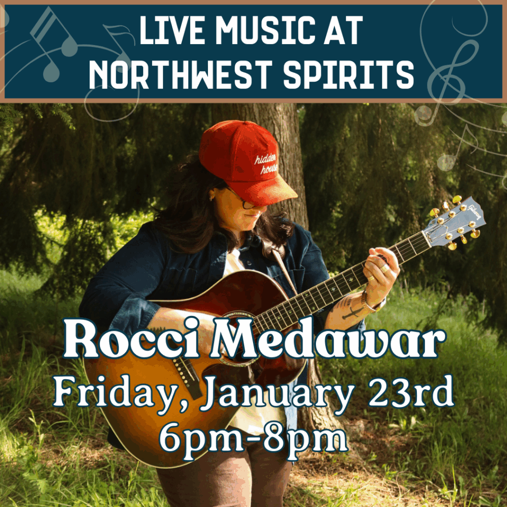 A local female singer-songwriter plays an acoustic guitar in a wooded outdoor setting, promoting a Live Music at Northwest Spirits event with Rocci Medawar on Friday, January 23 from 6pm to 8pm.